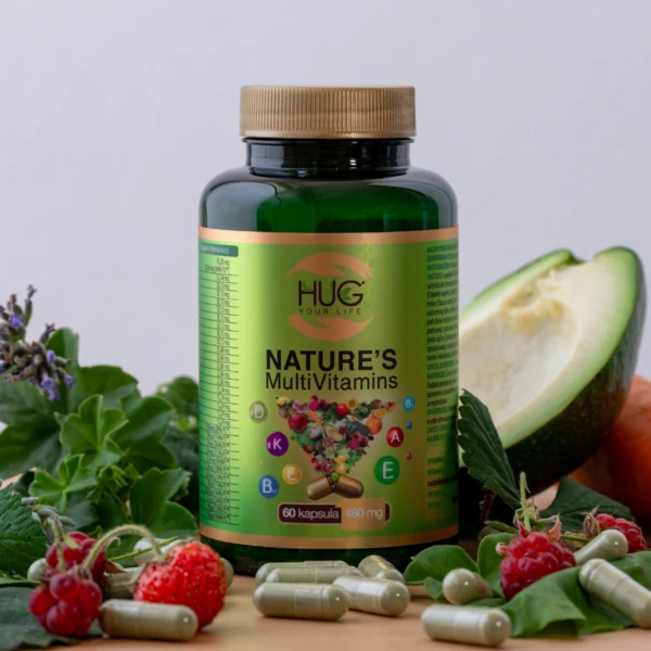 Bočica NATURE'S MultiVitamins proizvoda brenda Hug Your Life na stolu koji je pun voća: avokada, malina, jagoda i kapsula